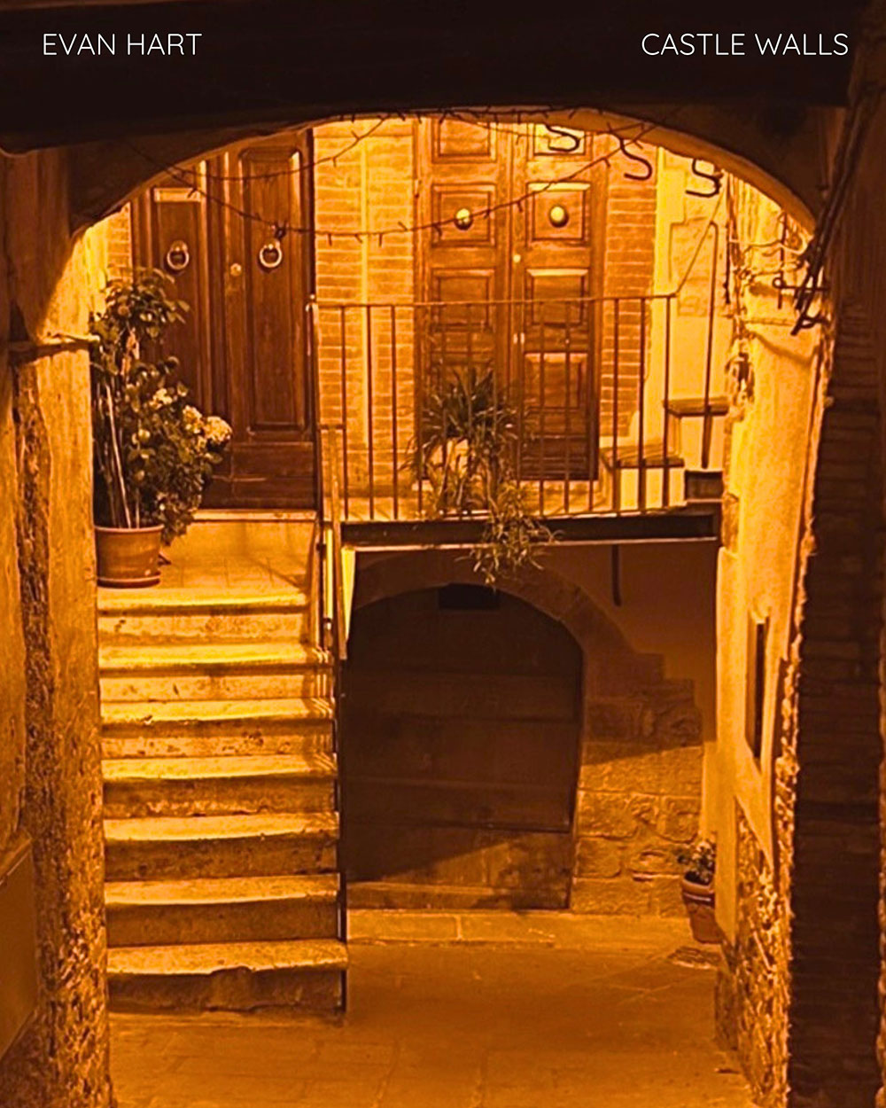 A graphic for the song "Castle Walls". It's of an outdoor stairwell lit by warm lighting at night.