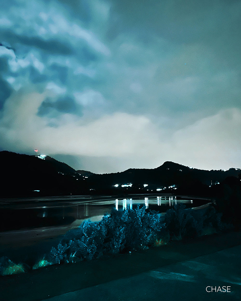 A graphic for the song "Chase". It's of the mountains and a lake, taken from the side of a street, presumably around twilight.